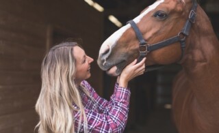 A woman and her horse in a barn