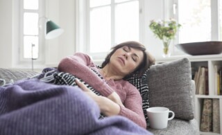 Woman who appears to be sick and resting on her couch