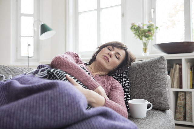 Woman who appears to be sick and resting on her couch
