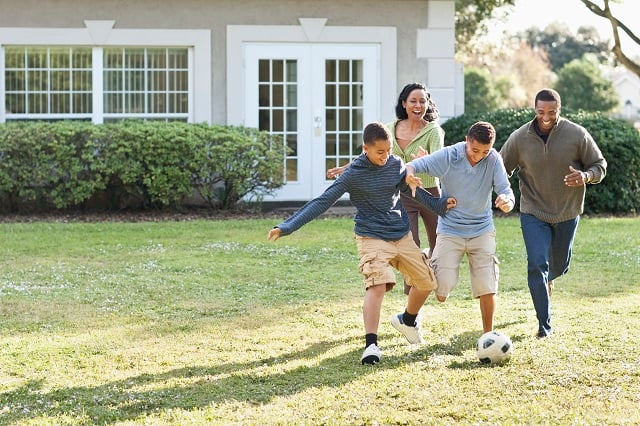 Family playing soccer in backyard