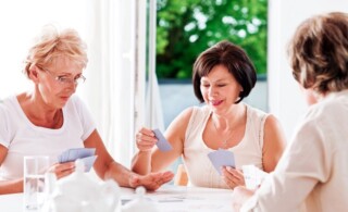 Three mature women playing cards together.