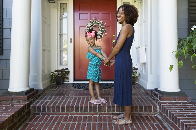 Portrait of mother and daughter on porch in front of red door with wreath