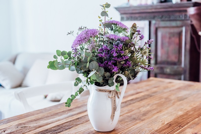 Close-up image of vase with lilac flowers on a wooden table (indoors)