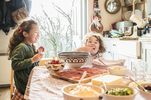 Country style kitchen with food, glassware and children eating