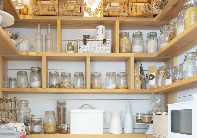 Woven baskets and food jars in pantry with built-in shelves