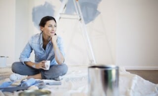 Woman relaxing with coffee among painting supplies