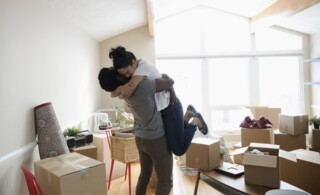 Couple hugging in new home, unpacking cardboard boxes