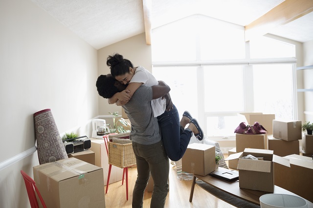 Couple hugging in new home, unpacking cardboard boxes