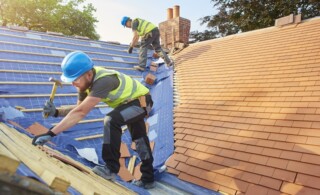 roofers nail down roof matting and tiles