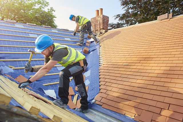 roofers nail down roof matting and tiles