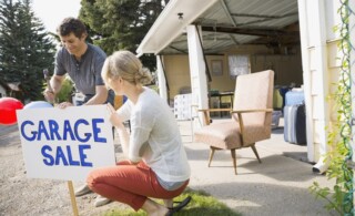 Couple putting up garage sale sign in yard