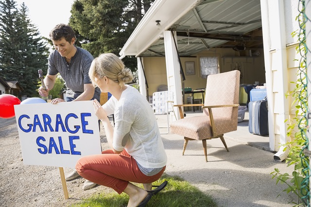 Couple putting up garage sale sign in yard
