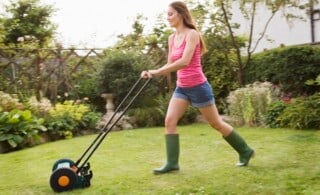 Woman mowing lawn with grass mower
