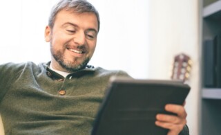 Man using digital smart home tablet on the couch