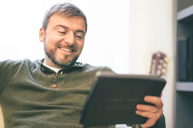 Man using digital smart home tablet on the couch