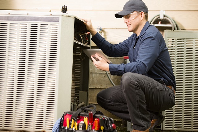 HVAC repair man working on an exterior AC unit