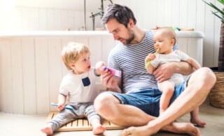 father and two kids sitting on tile shower floor