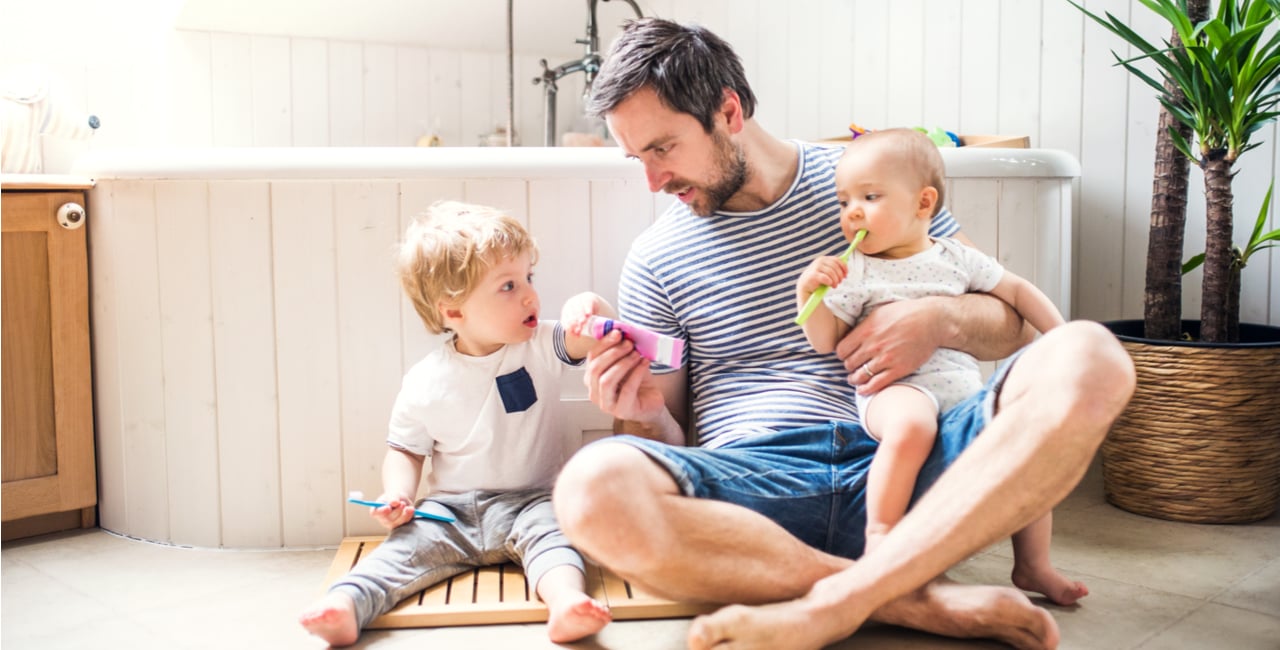 father and two kids sitting on tile shower floor