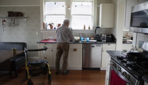 Senior man doing dishes in his kitchen with his walker