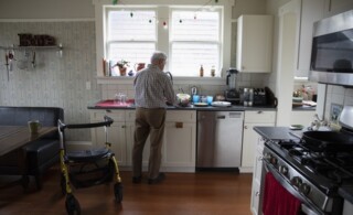 Senior man doing dishes in his kitchen with his walker