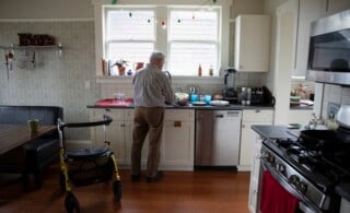 Senior man doing dishes in his kitchen with his walker