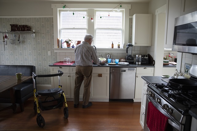 Senior man doing dishes in his kitchen with his walker