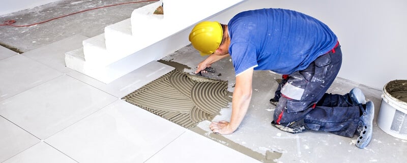installer adds ceramic tile to basement floor