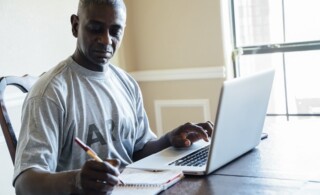 Middle aged man in army shirt working on laptop at home