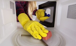 woman scrubs a microwave