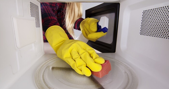 woman scrubs a microwave