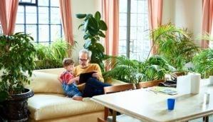 Grandfather and grandson on couch surrounded by live palms, ficus, and ferns.