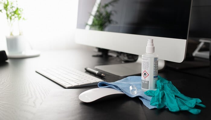 disinfectant and gloves near computer surfaces touched frequently