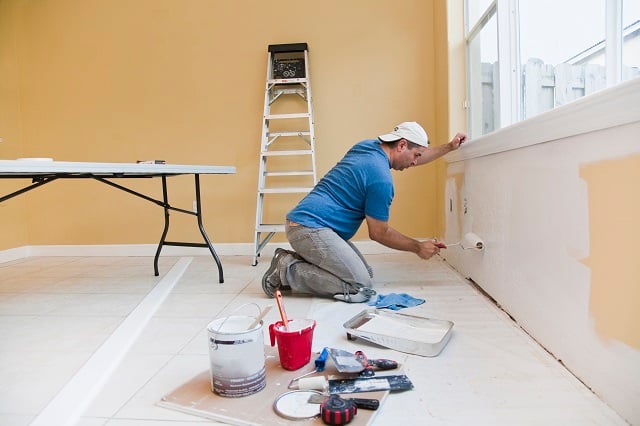 Man painting wall with roller in the house