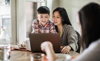 Mother and child working on the computer together at the dining room table