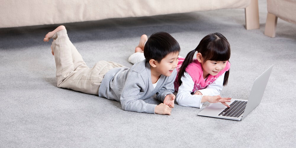 kids play on computer on a carpet in room