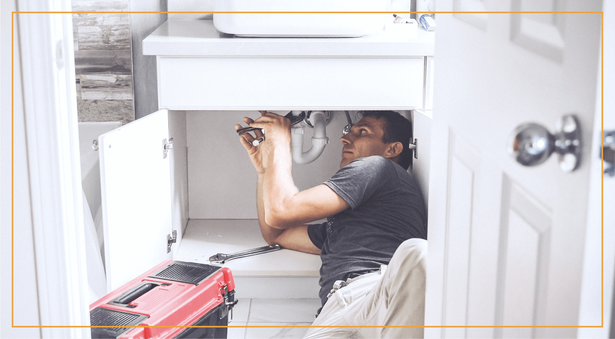 plumber under sink in kitchen