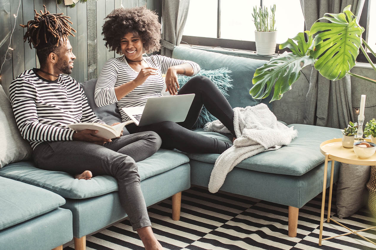 couple laughs in comfortable home while doing research