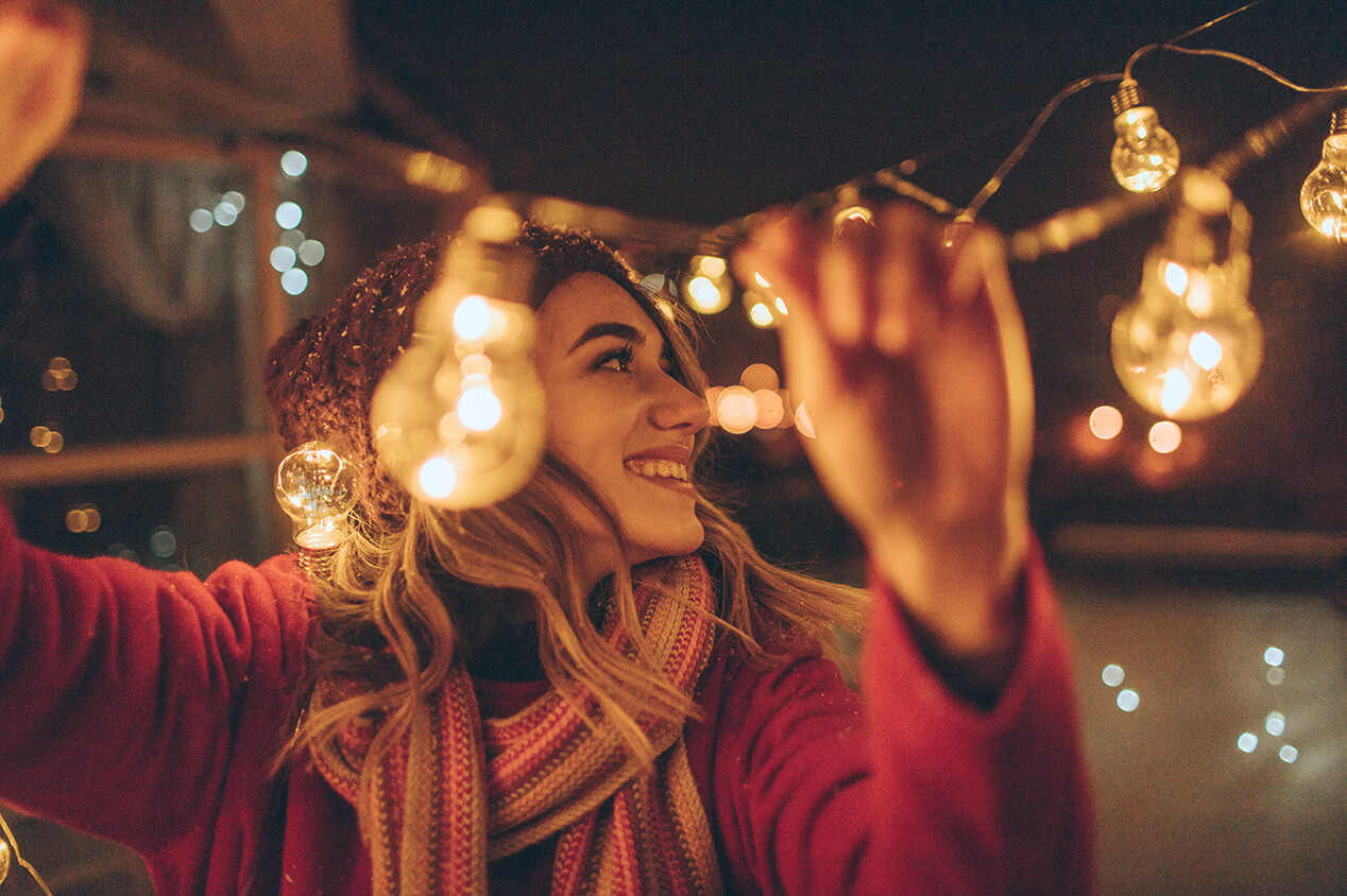 woman hanging up string lights