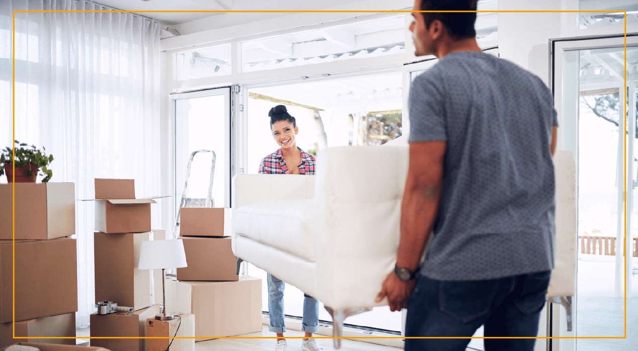 couple moving sofa into house