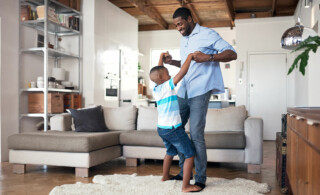 Father and son dancing in living room