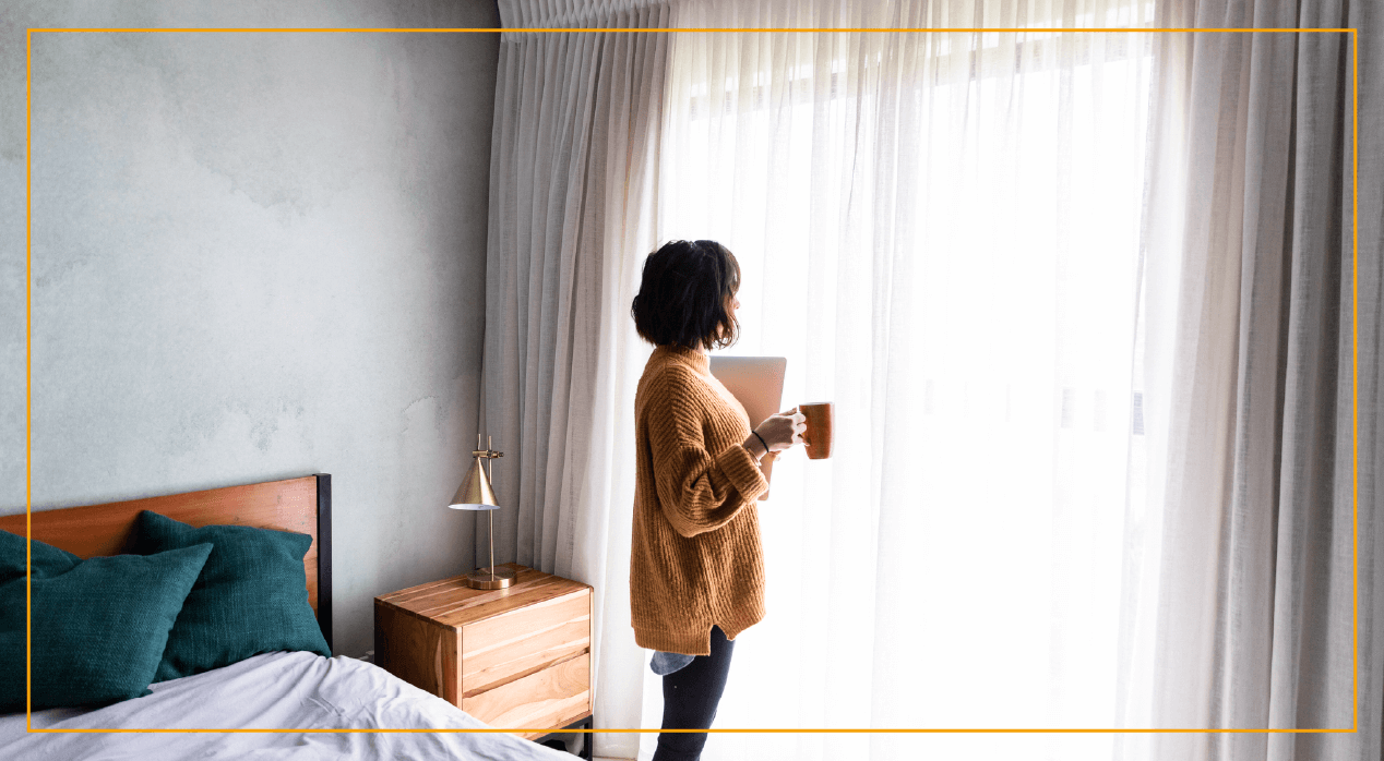 Woman standing by windows with coffee mug