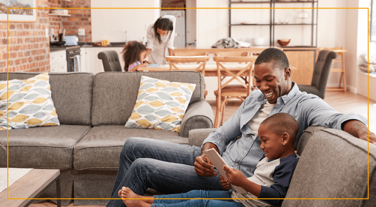 Father and son sitting on couch looking at iPad 