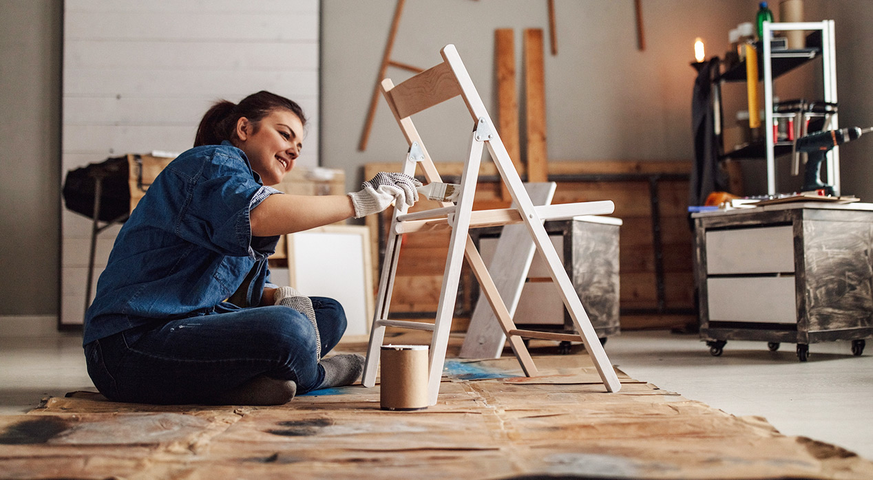 woman painting chair in garage