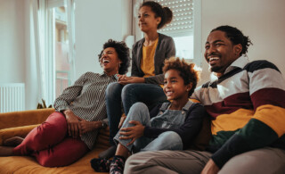 happy family watching movie on couch