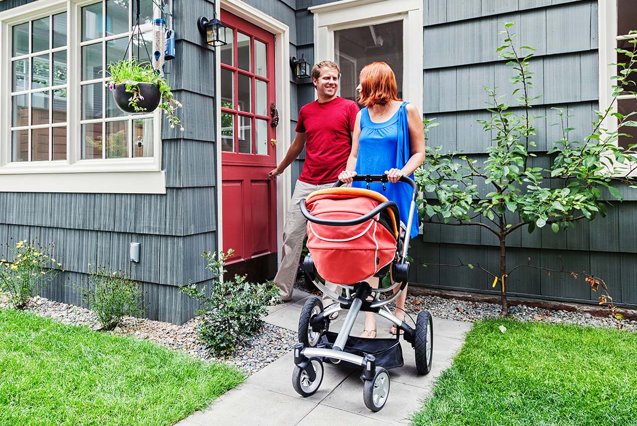 young family on their way out to take a walk with their new baby in a stroller