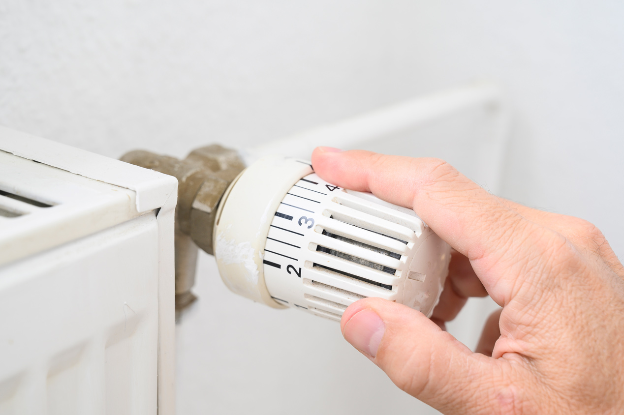 A man’s hand adjusting the temperature of a radiator