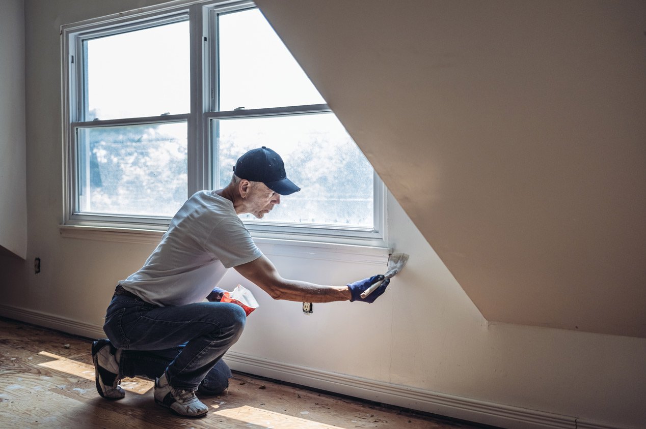 A man painting a wall in an empty apartment