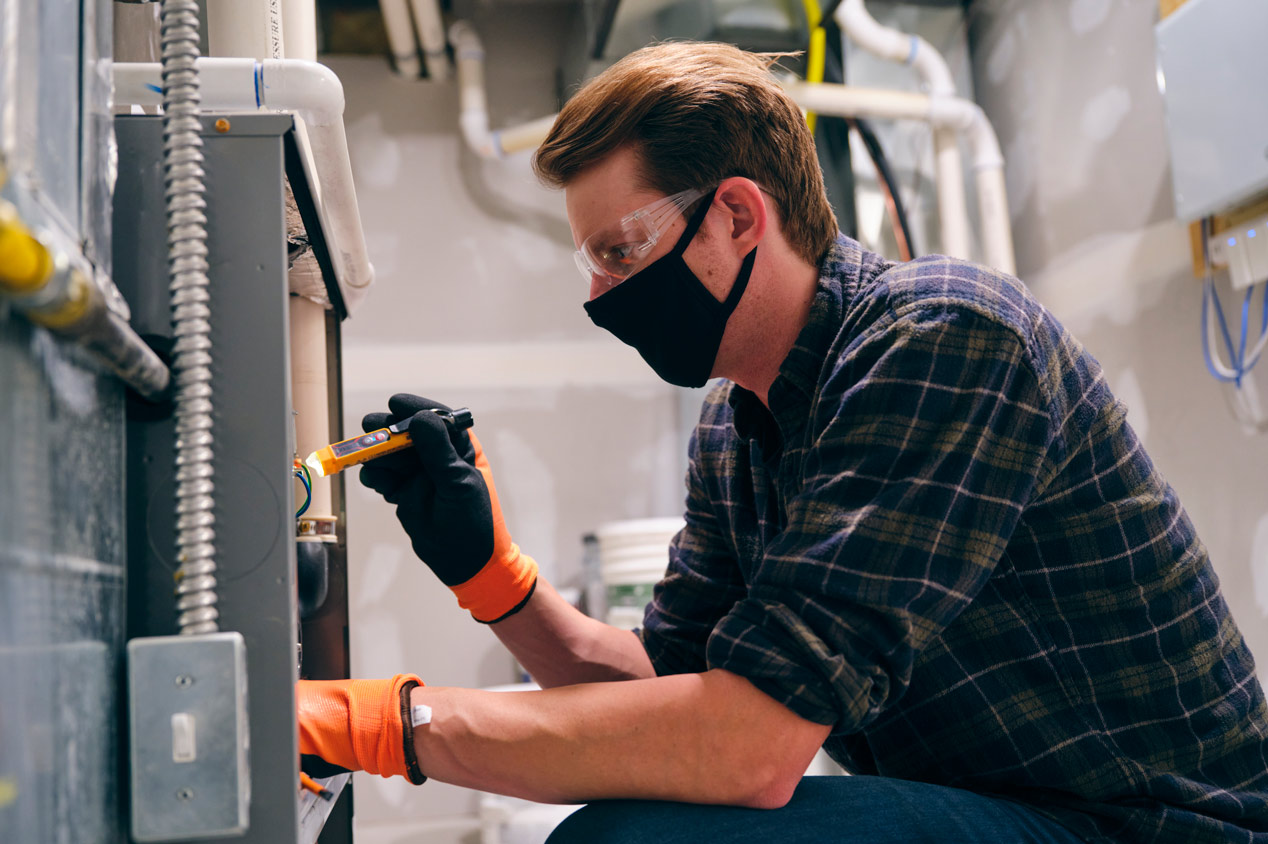 A professional repairing a furnace at house’s basement