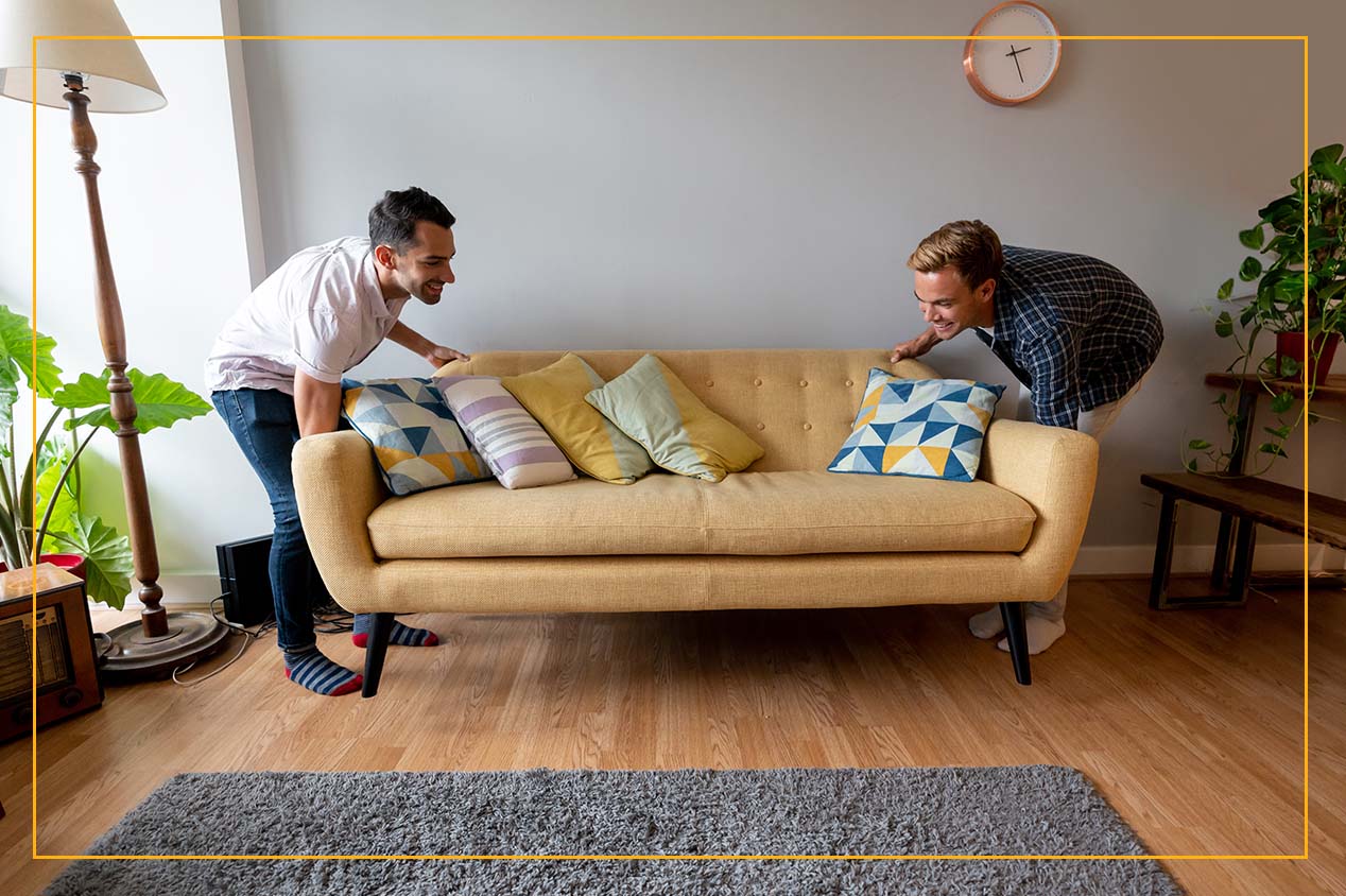 two guys moving couch in living room