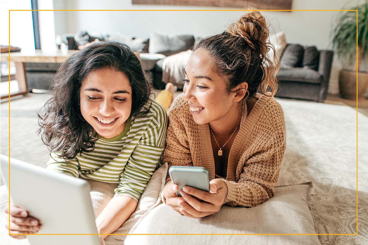 girls on the rug laughing with mobile devices